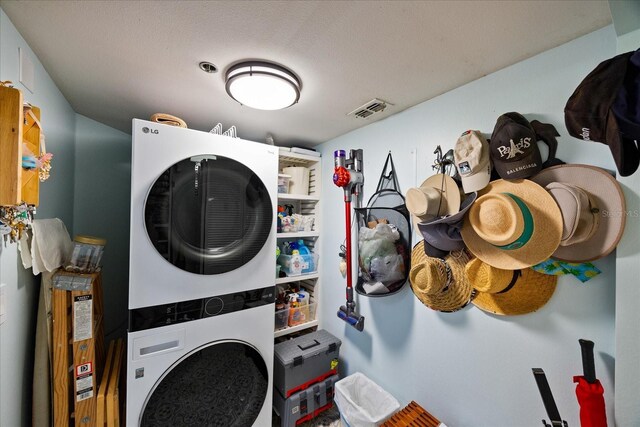washroom featuring visible vents, stacked washer and clothes dryer, and laundry area