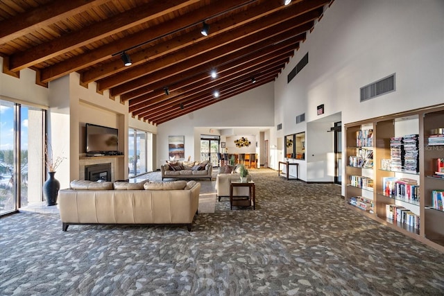 carpeted living area featuring high vaulted ceiling, beamed ceiling, rail lighting, and visible vents
