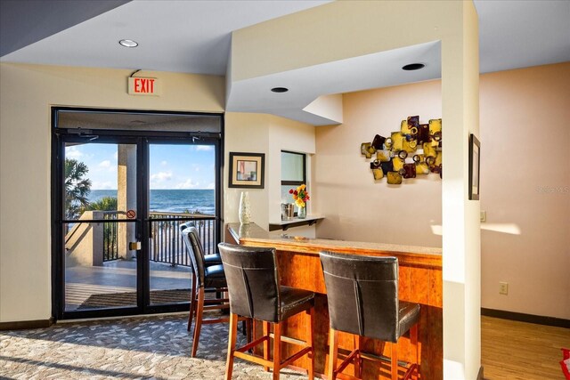 bar featuring a bar, wood finished floors, baseboards, and recessed lighting