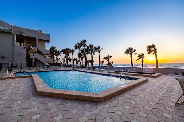 pool featuring a patio and a water view