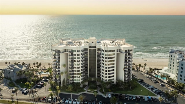 aerial view at dusk with a view of the beach and a water view