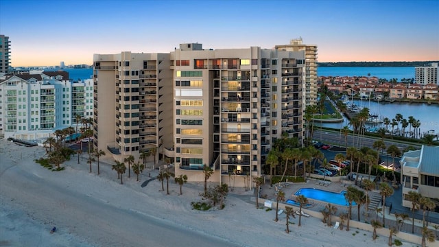 property at dusk with a water view and a view of city