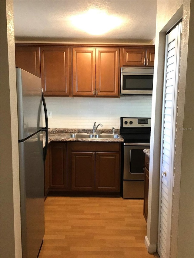 2625 State Road 590 Unit 1822, Clearwater, FL 33759 - kitchen featuring a sink, appliances with stainless steel finishes, light wood finished floors, stone counters, and backsplash