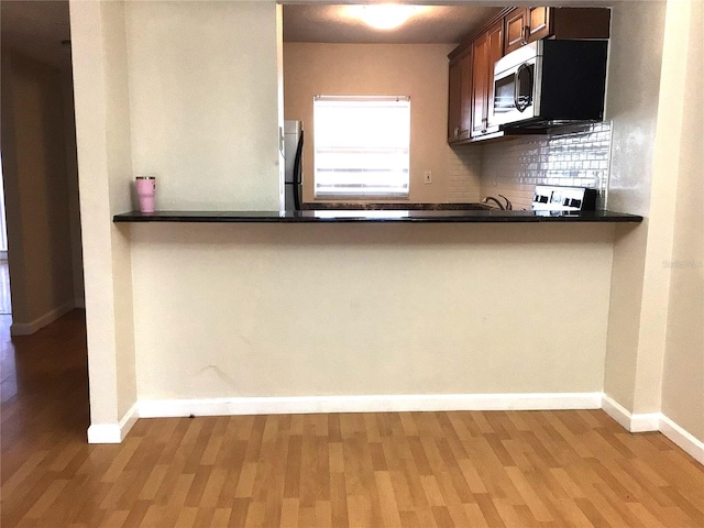 2625 State Road 590 Unit 1822, Clearwater, FL 33759 - kitchen with stainless steel microwave, dark countertops, decorative backsplash, and wood finished floors
