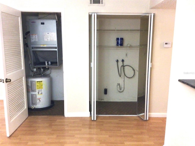 2625 State Road 590 Unit 1822, Clearwater, FL 33759 - bathroom featuring visible vents, baseboards, heating unit, electric water heater, and wood finished floors