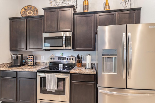 kitchen with stainless steel appliances, light stone countertops, and dark brown cabinets