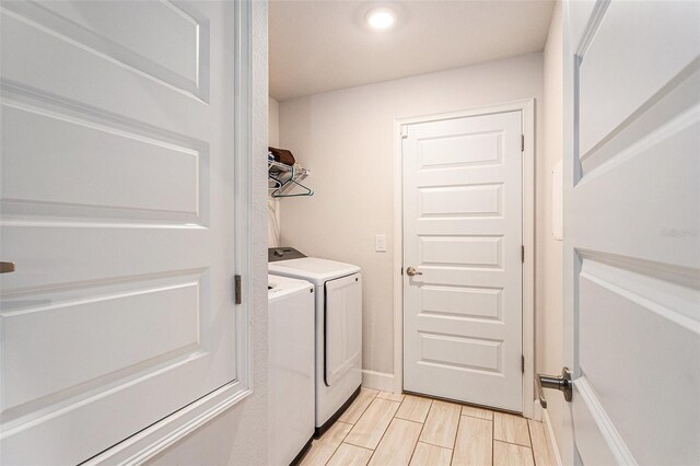 laundry room featuring laundry area, washing machine and clothes dryer, and wood finish floors