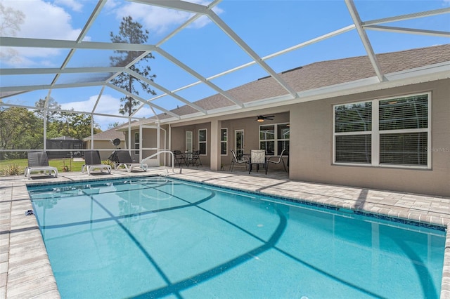 outdoor pool featuring a patio, a ceiling fan, and glass enclosure