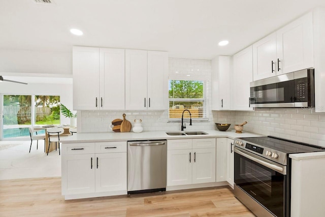 1886 San Mateo Dr, Dunedin, FL 34698 - kitchen featuring a wealth of natural light, appliances with stainless steel finishes, white cabinetry, and a sink