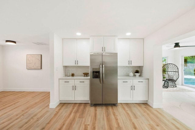 1886 San Mateo Dr, Dunedin, FL 34698 - kitchen featuring light wood-style flooring, backsplash, white cabinetry, and stainless steel fridge with ice dispenser