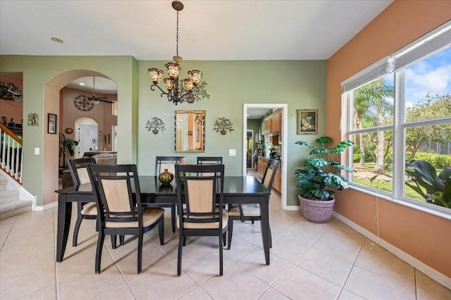 dining space with arched walkways, a notable chandelier, light tile patterned flooring, and baseboards