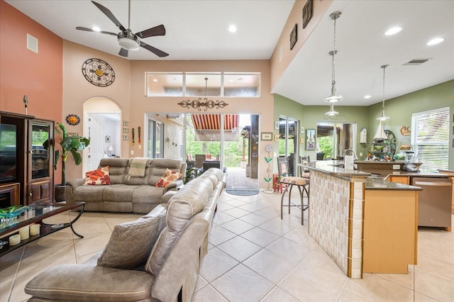 living room featuring a ceiling fan, a towering ceiling, visible vents, and recessed lighting