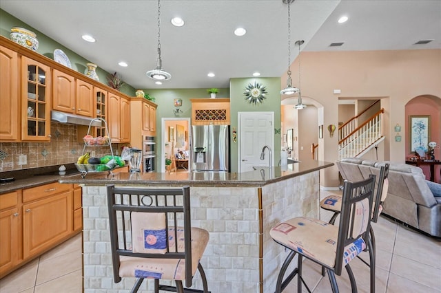 kitchen with visible vents, light tile patterned floors, glass insert cabinets, appliances with stainless steel finishes, and a breakfast bar area