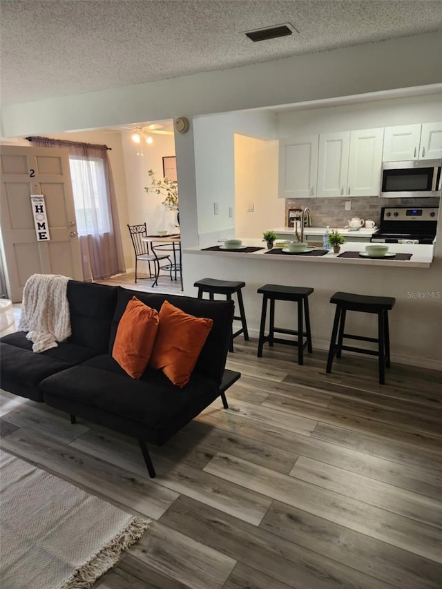 living room with a textured ceiling, wood finished floors, and visible vents