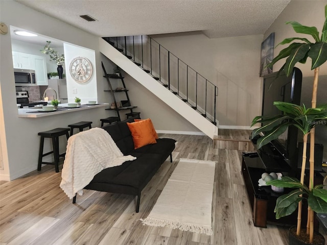 interior space with light wood-type flooring, a textured ceiling, visible vents, and stairs