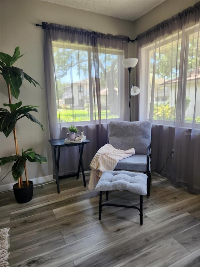 living area with a textured ceiling, wood finished floors, and baseboards
