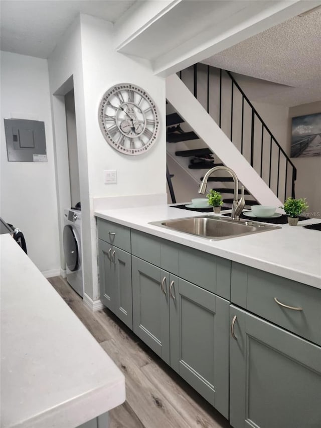 interior space featuring laundry area, washer / clothes dryer, electric panel, a sink, and light wood finished floors