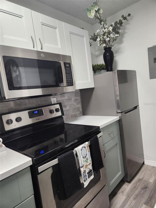 kitchen with electric panel, light countertops, appliances with stainless steel finishes, light wood finished floors, and backsplash