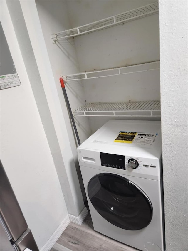 laundry room featuring washer / clothes dryer, laundry area, wood finished floors, and baseboards
