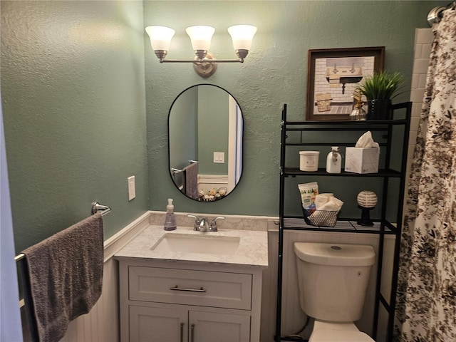 bathroom featuring a notable chandelier, vanity, and toilet