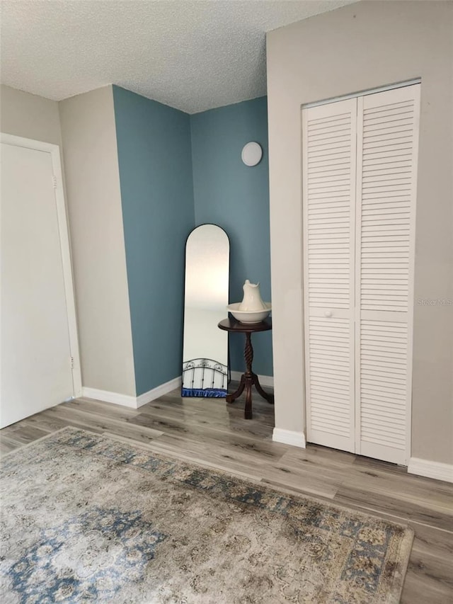 unfurnished room featuring baseboards, wood finished floors, and a textured ceiling