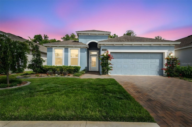 view of front of house featuring a garage, stucco siding, a front lawn, and decorative driveway