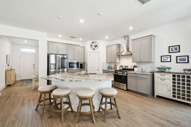 kitchen featuring a sink, wall chimney range hood, gray cabinetry, and stainless steel appliances