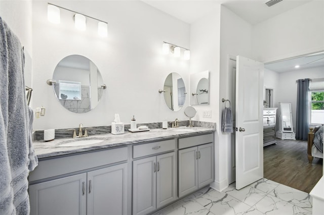 ensuite bathroom featuring double vanity, ensuite bath, marble finish floor, and a sink