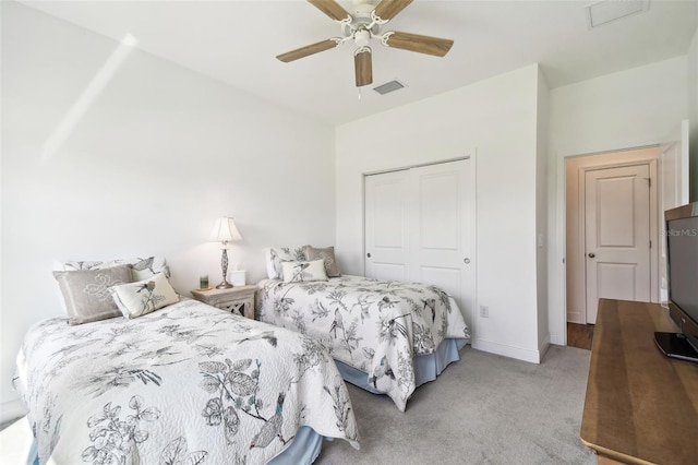 carpeted bedroom with a closet, baseboards, a ceiling fan, and visible vents