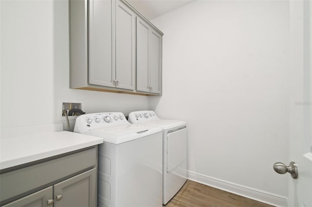 laundry room featuring cabinet space, independent washer and dryer, light wood-type flooring, and baseboards