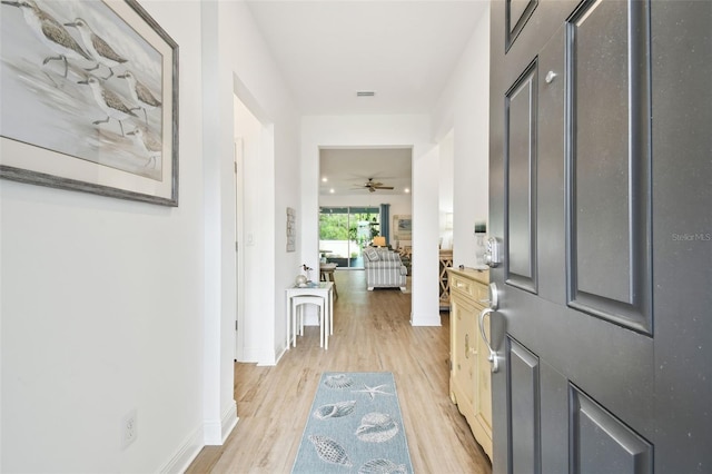 entrance foyer with light wood finished floors, baseboards, a ceiling fan, and visible vents