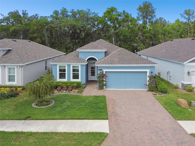 view of front of house with an attached garage, stucco siding, a front lawn, and decorative driveway