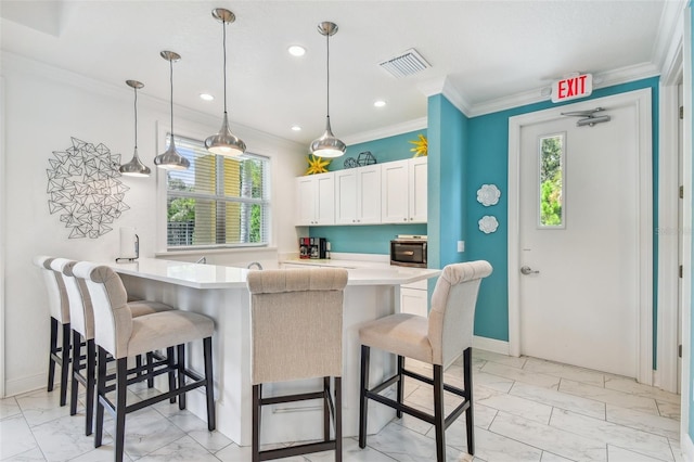 kitchen with ornamental molding, visible vents, a kitchen breakfast bar, and marble finish floor