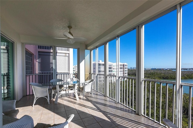 sunroom featuring tile patterned flooring, a ceiling fan, and a healthy amount of sunlight