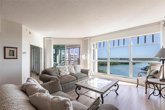living room with a textured ceiling, wood finished floors, and a water view
