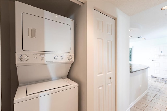 laundry room with light tile patterned floors, stacked washer and dryer, and laundry area