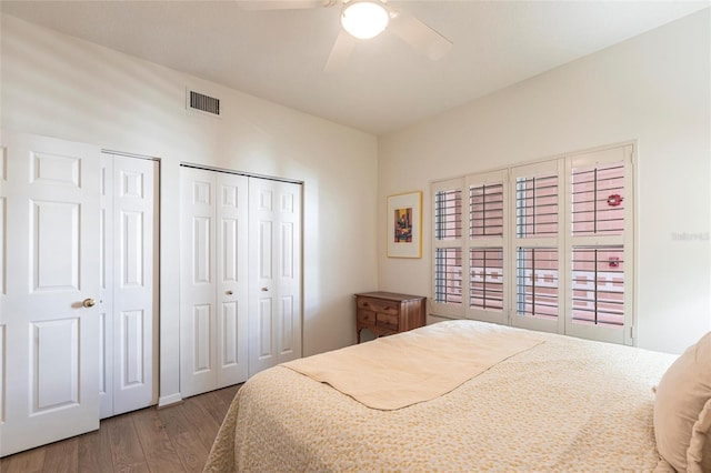 bedroom with visible vents, multiple closets, ceiling fan, and wood finished floors
