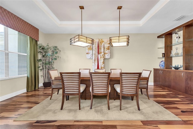 dining space with visible vents, wood finished floors, a raised ceiling, and baseboards