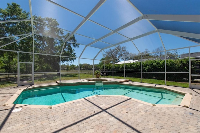 view of swimming pool featuring glass enclosure, a pool with connected hot tub, and a patio area