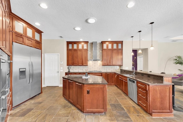 5807 Thoreau Pl, Lithia, FL 33547 - kitchen featuring appliances with stainless steel finishes, wall chimney exhaust hood, a peninsula, a textured ceiling, and backsplash