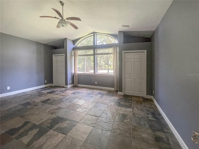 5807 Thoreau Pl, Lithia, FL 33547 - empty room featuring vaulted ceiling, a ceiling fan, a textured ceiling, baseboards, and stone tile flooring