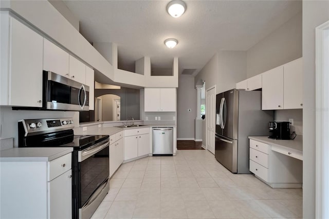 11626 Pure Pebble Dr, Riverview, FL 33569 - kitchen with appliances with stainless steel finishes, a sink, arched walkways, light countertops, and white cabinetry