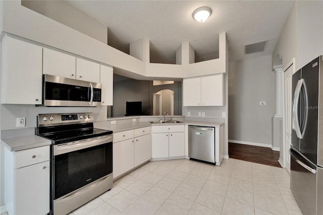 11626 Pure Pebble Dr, Riverview, FL 33569 - kitchen with appliances with stainless steel finishes, a sink, light countertops, white cabinetry, and arched walkways