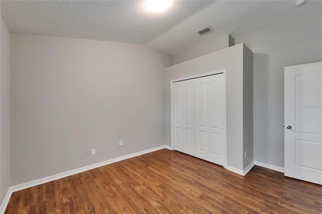 11626 Pure Pebble Dr, Riverview, FL 33569 - unfurnished bedroom with wood finished floors, baseboards, lofted ceiling, a closet, and a textured ceiling