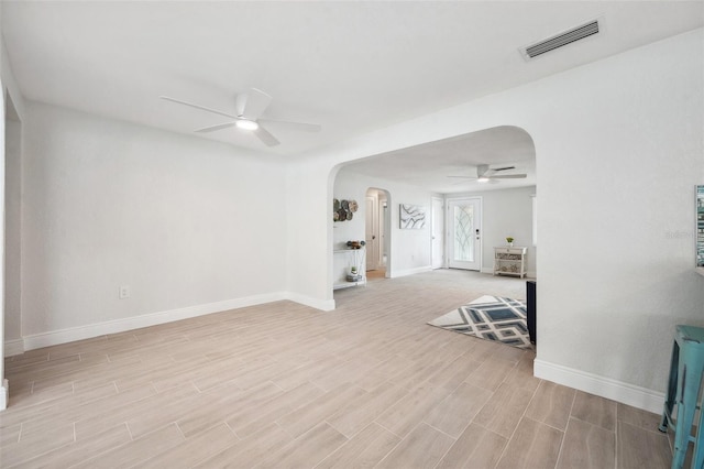 unfurnished room featuring arched walkways, wood finish floors, a ceiling fan, and visible vents