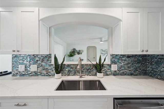 kitchen with ceiling fan, arched walkways, white cabinets, dishwasher, and a sink