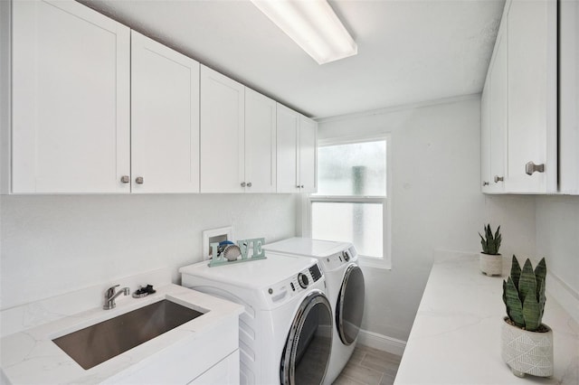 washroom featuring light wood-style flooring, separate washer and dryer, a sink, baseboards, and cabinet space