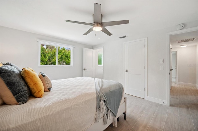 bedroom featuring visible vents, baseboards, a ceiling fan, and light wood-style floors