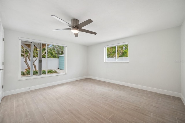 spare room featuring light wood-style flooring, ceiling fan, and baseboards