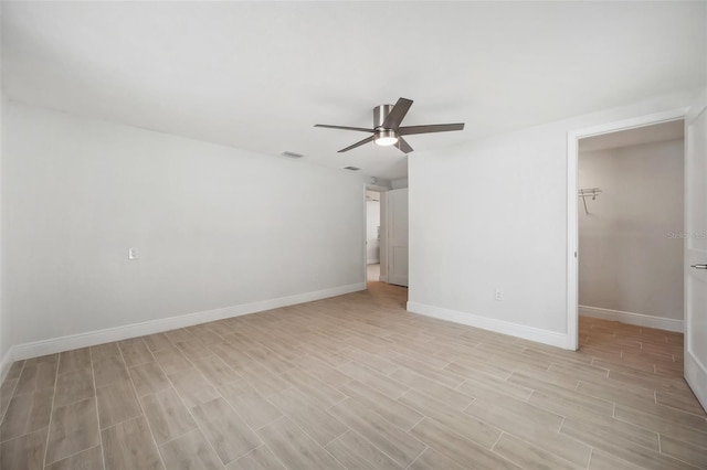 spare room featuring light wood-type flooring, visible vents, baseboards, and a ceiling fan